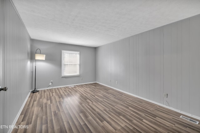 spare room featuring hardwood / wood-style flooring and wooden walls