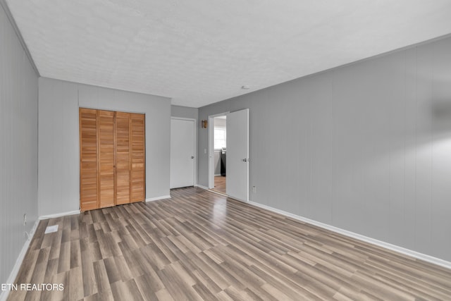 unfurnished bedroom with wood walls, light hardwood / wood-style flooring, and a closet