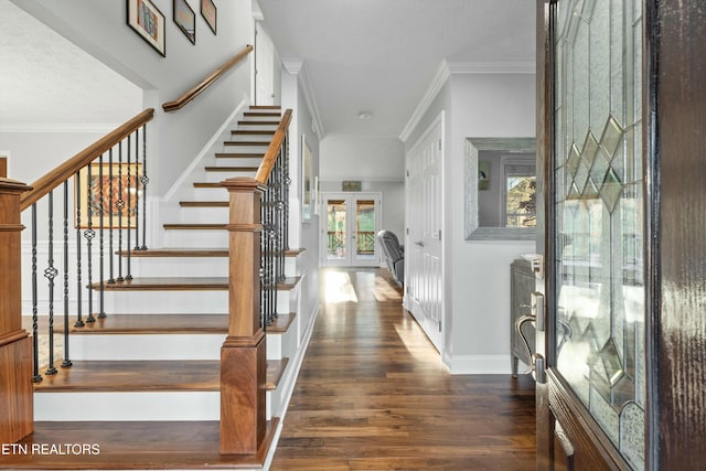 foyer featuring a textured ceiling, ornamental molding, dark wood-type flooring, and french doors