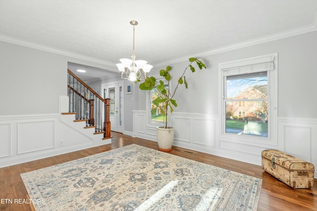 foyer featuring crown molding, hardwood / wood-style flooring, and an inviting chandelier