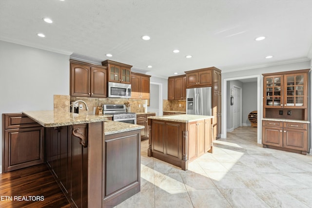 kitchen featuring kitchen peninsula, backsplash, light stone counters, ornamental molding, and stainless steel appliances