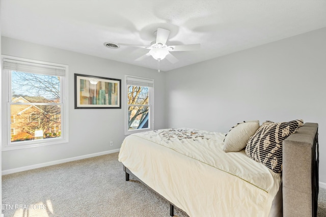 bedroom featuring light carpet, multiple windows, and ceiling fan