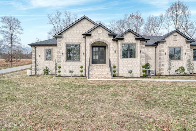 french provincial home with central air condition unit, french doors, and a front lawn