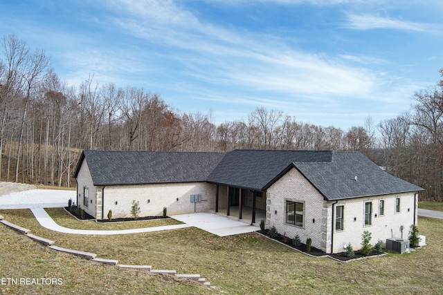 rear view of property featuring a patio, central air condition unit, and a lawn