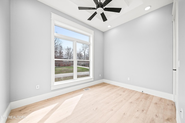 empty room with plenty of natural light, light hardwood / wood-style floors, and ceiling fan