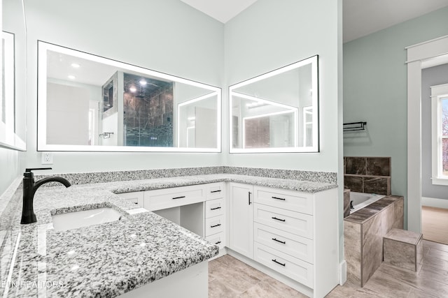 bathroom with vanity and a relaxing tiled tub