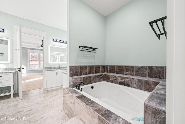 bathroom with vanity, a relaxing tiled tub, and ceiling fan