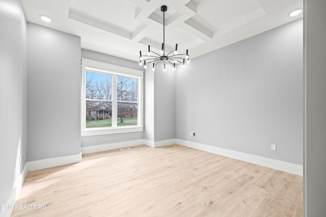 unfurnished room featuring beam ceiling, light hardwood / wood-style floors, an inviting chandelier, and coffered ceiling