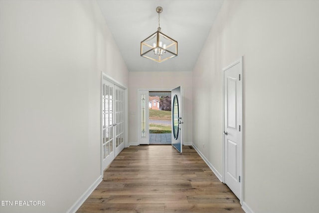 doorway to outside with french doors, wood-type flooring, and an inviting chandelier