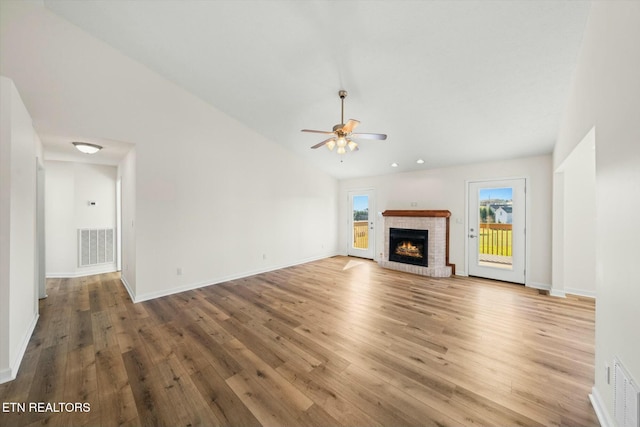 unfurnished living room with hardwood / wood-style flooring, ceiling fan, lofted ceiling, and a fireplace