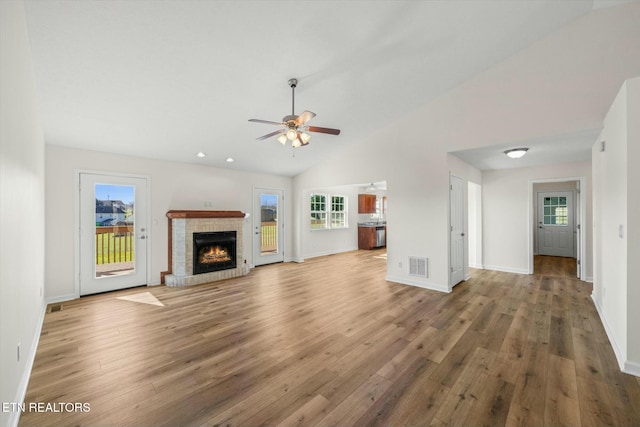 unfurnished living room with hardwood / wood-style flooring, ceiling fan, a fireplace, and high vaulted ceiling