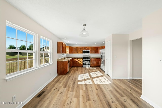 kitchen with pendant lighting, sink, light wood-type flooring, and stainless steel appliances