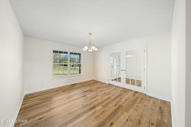 spare room featuring light wood-type flooring and a notable chandelier