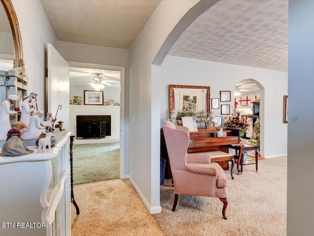 hall featuring light carpet and a textured ceiling