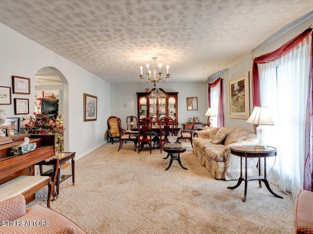 carpeted living room featuring a textured ceiling and an inviting chandelier