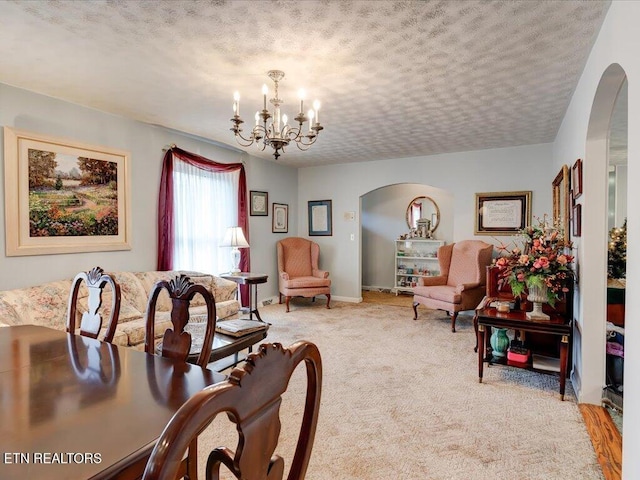 carpeted dining area featuring a textured ceiling and an inviting chandelier