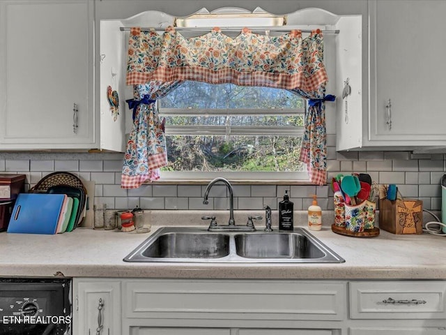 kitchen with dishwashing machine, white cabinetry, sink, and tasteful backsplash