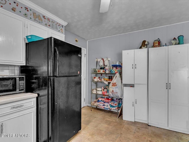 kitchen featuring black fridge, white cabinetry, and a textured ceiling