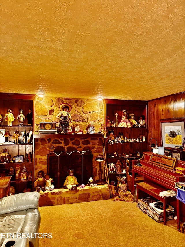 carpeted living room featuring a textured ceiling, wood walls, and a fireplace