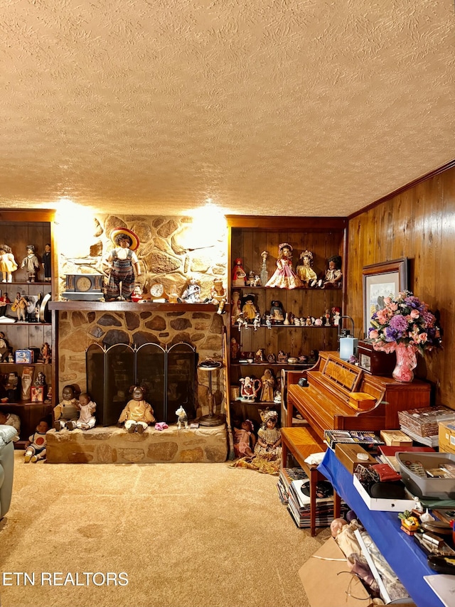 interior space featuring wood walls, a textured ceiling, a fireplace, and carpet floors