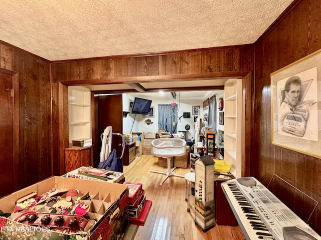 interior space featuring a textured ceiling, light hardwood / wood-style flooring, and wooden walls