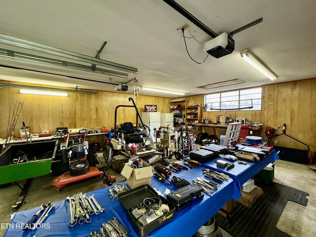 garage featuring a workshop area, wooden walls, and a garage door opener