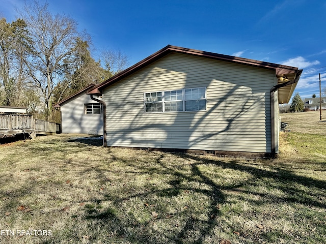 view of side of property with a wooden deck and a yard