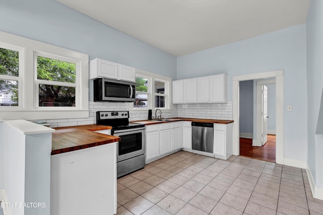 kitchen featuring wooden counters, backsplash, stainless steel appliances, and white cabinets