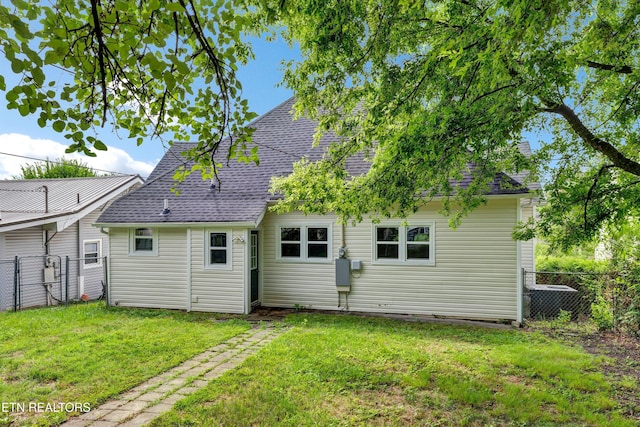 rear view of house with a yard and cooling unit