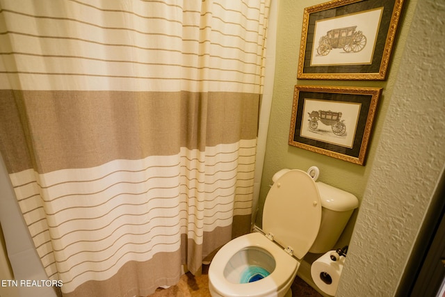 bathroom with curtained shower and toilet