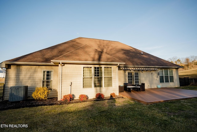 back of property with central AC unit, a deck, and a lawn