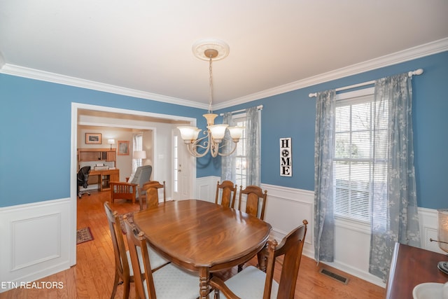 dining space with a chandelier, ornamental molding, and light hardwood / wood-style flooring