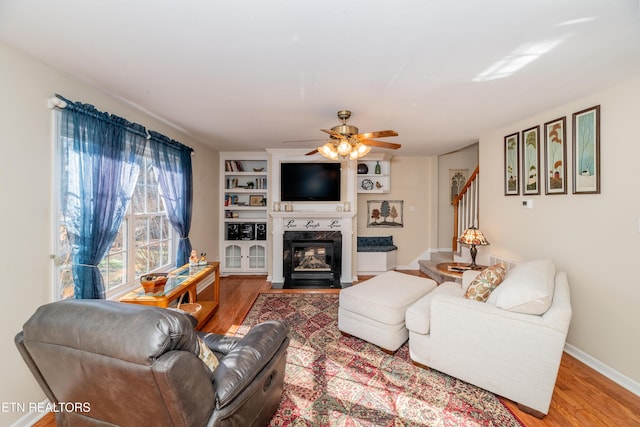 living room with wood-type flooring, ceiling fan, and built in shelves