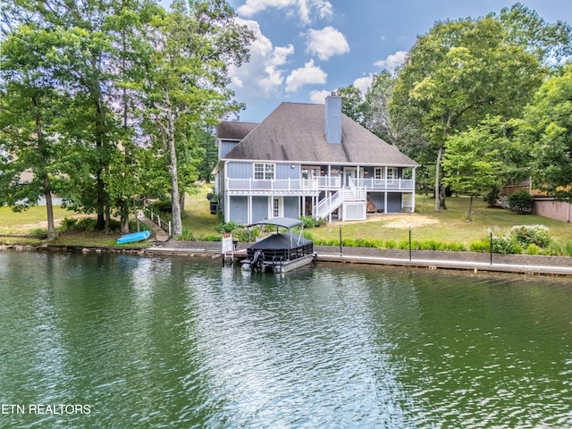 rear view of property featuring a lawn and a deck with water view