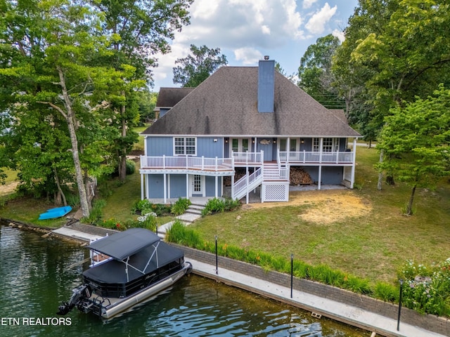 back of property with a yard and a water view