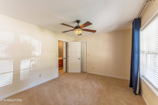 spare room featuring a healthy amount of sunlight, ceiling fan, and light colored carpet