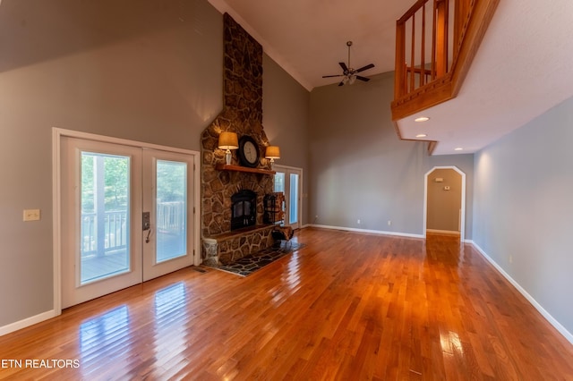 unfurnished living room featuring a fireplace, hardwood / wood-style floors, high vaulted ceiling, and ceiling fan