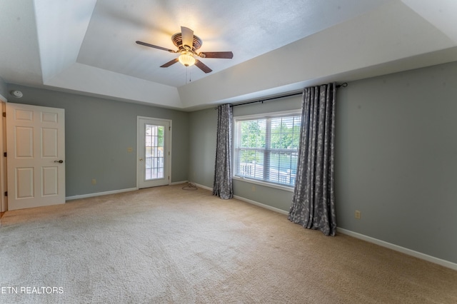 spare room featuring a tray ceiling, ceiling fan, and light colored carpet