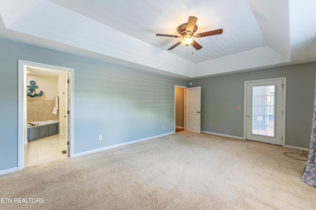 spare room with a tray ceiling, ceiling fan, and light colored carpet