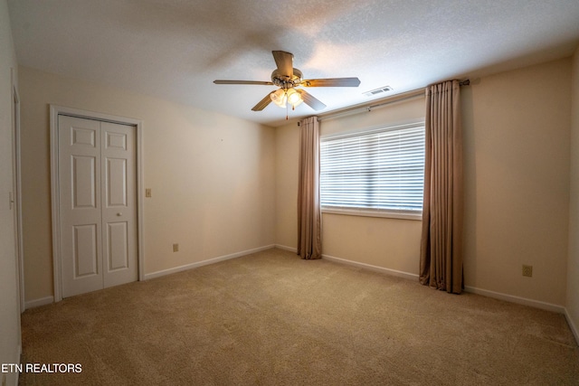 carpeted empty room featuring ceiling fan and a textured ceiling