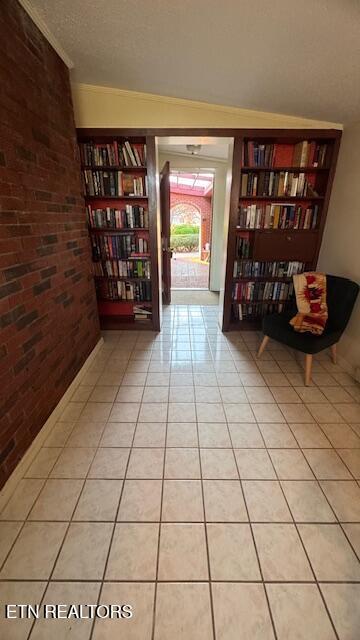 207 Gaut Ave, Sweetwater, TN 37874 - unfurnished room featuring a textured ceiling, wall of books, light tile patterned floors, and brick wall