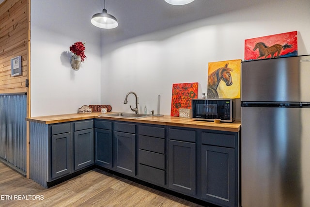 kitchen featuring light wood-type flooring, stainless steel refrigerator, butcher block counters, and sink