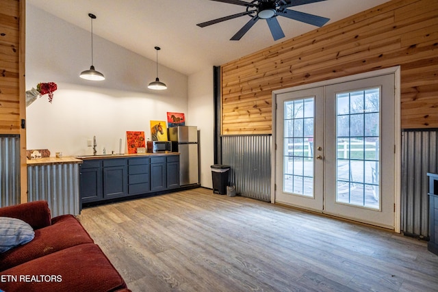 living room with french doors, light hardwood / wood-style floors, wooden walls, and sink