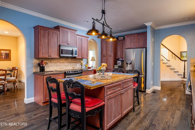 kitchen with appliances with stainless steel finishes, a kitchen island, hanging light fixtures, and crown molding