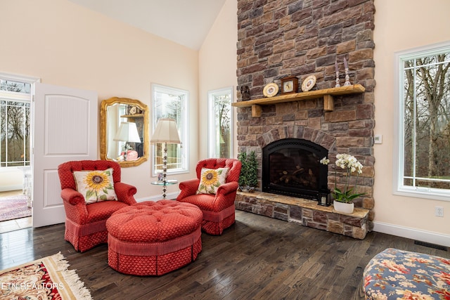 sitting room with high vaulted ceiling, dark hardwood / wood-style floors, and a stone fireplace