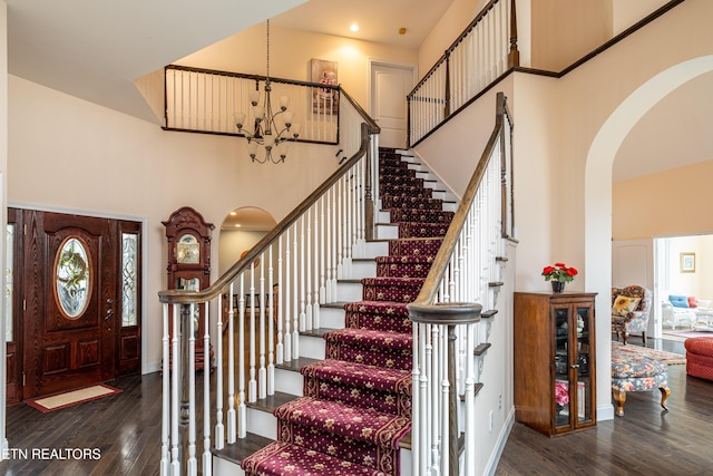 foyer entrance with a notable chandelier, dark hardwood / wood-style flooring, and a high ceiling