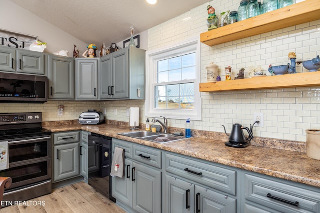 kitchen with backsplash, sink, vaulted ceiling, light hardwood / wood-style floors, and stainless steel appliances