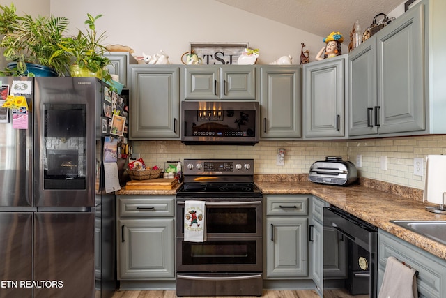 kitchen with tasteful backsplash, gray cabinetry, stainless steel appliances, and vaulted ceiling