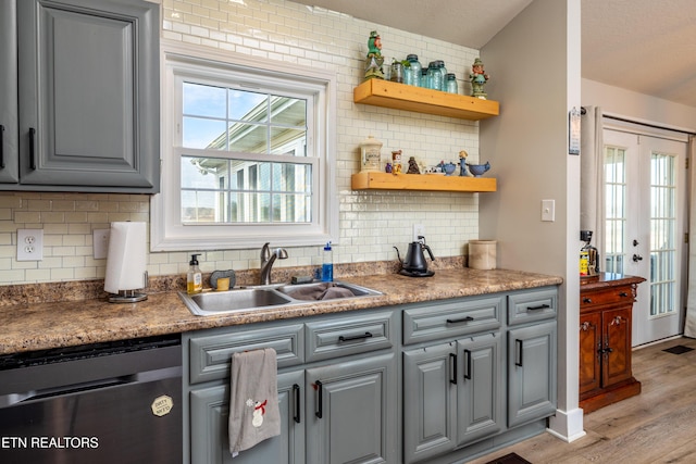 kitchen with stainless steel dishwasher, gray cabinets, light wood-type flooring, and sink