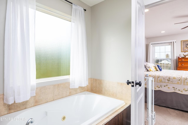 bathroom featuring a relaxing tiled tub and ceiling fan